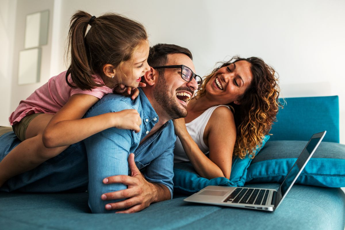 Happy family lying on bed and watching something on laptop